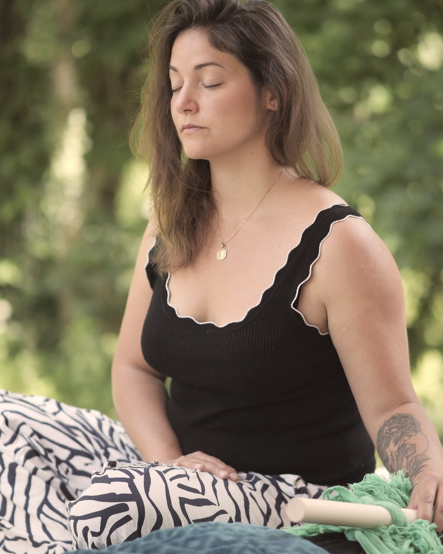 Roxane assise en extérieur, les yeux fermés, dans un temps de recueillement